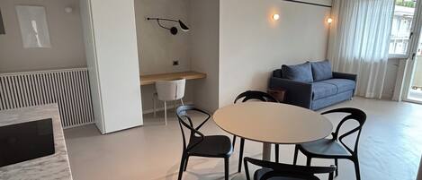 A modern living space with a dining area, a sofa, and a desk.