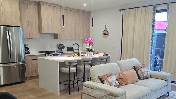Una cocina moderna con una isla central, electrodomésticos de acero inoxidable y armarios de madera.