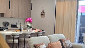 Una cocina moderna con una isla central, taburetes de bar y un comedor.