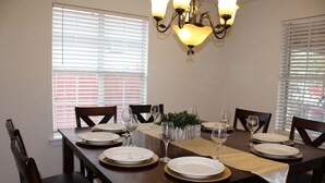 A dining table set for six with plates, glasses, and a centerpiece.