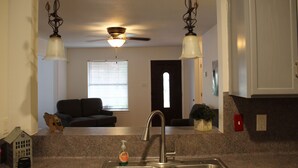 A kitchen with granite countertops, a stainless steel sink, and pendant lights.