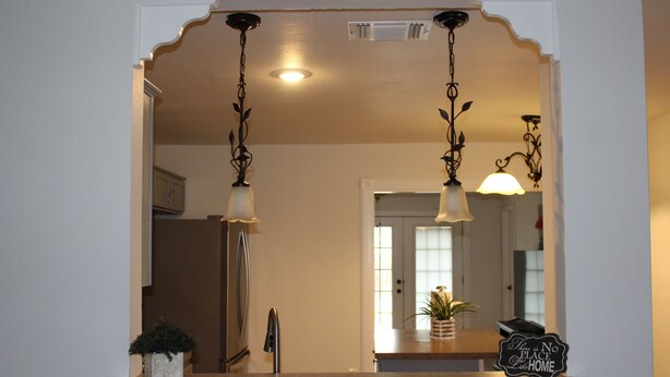 A kitchen with a marble countertop, a potted plant, and a sign stating "There is no place like home."
