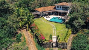 A large house with a swimming pool, surrounded by lush greenery and a clear sky. -  Luxury Beachfront Villa with Direct Beach Access. Hacienda Pinilla. Tamarindo. (Tamarindo)