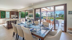 A modern dining area with a glass table, chairs, and a view of the outdoors. -  Luxury Beachfront Villa with Direct Beach Access. Hacienda Pinilla. Tamarindo. (Tamarindo)