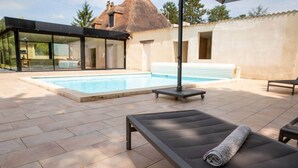 A modern outdoor pool area with a glass-enclosed lounge, a sunbed, and a pergola. - Le Rocal, close to Monbazillac in the shadow of Bergerac (Pomport)