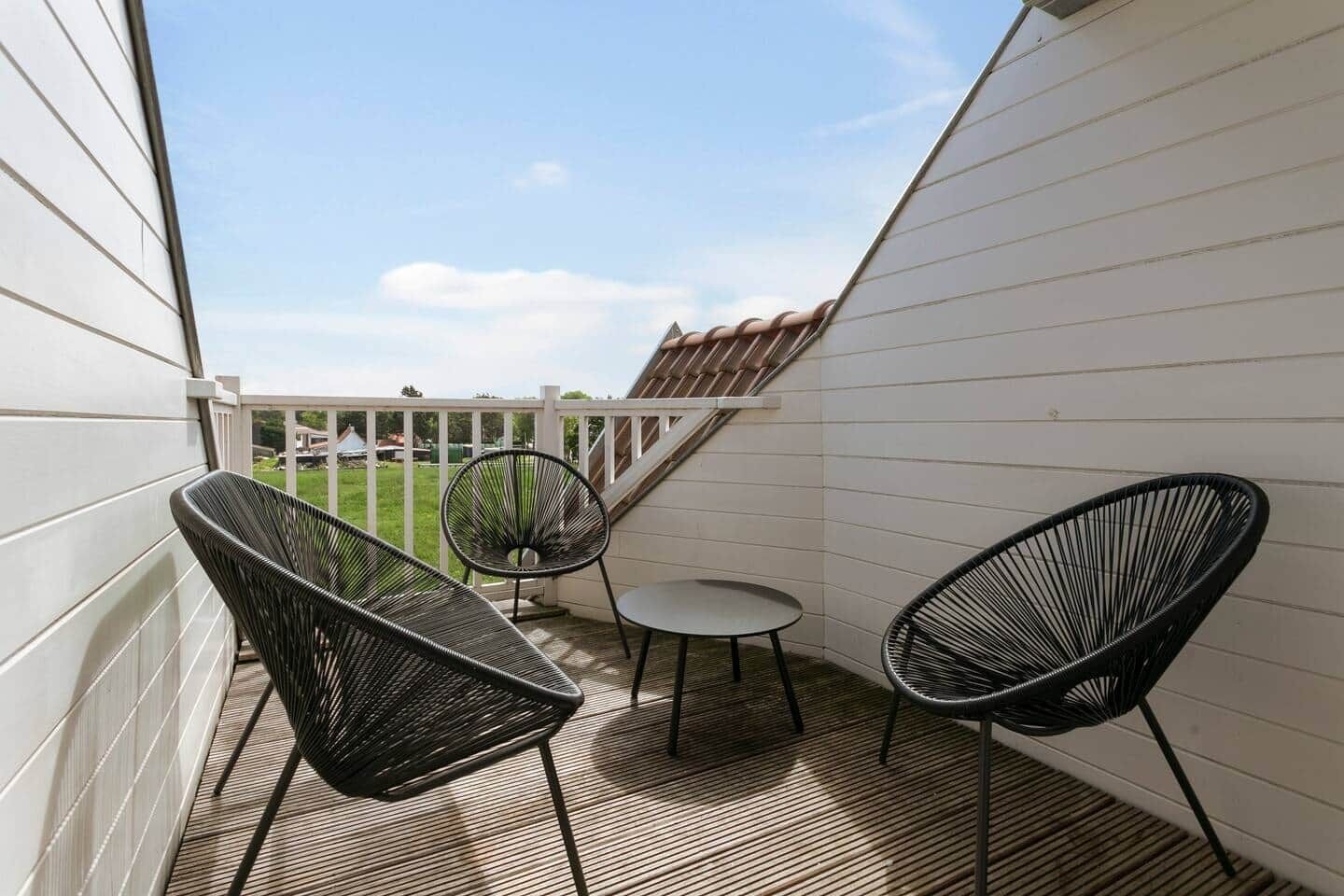 A balcony with two black wire mesh chairs and a small round table.
