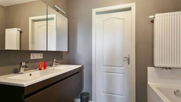 A bathroom with two sinks, a mirror, a door, and a radiator.
