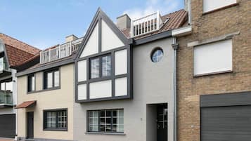 Een woonhuis met twee verdiepingen, een puntdak, dakkapellen en een balkon.