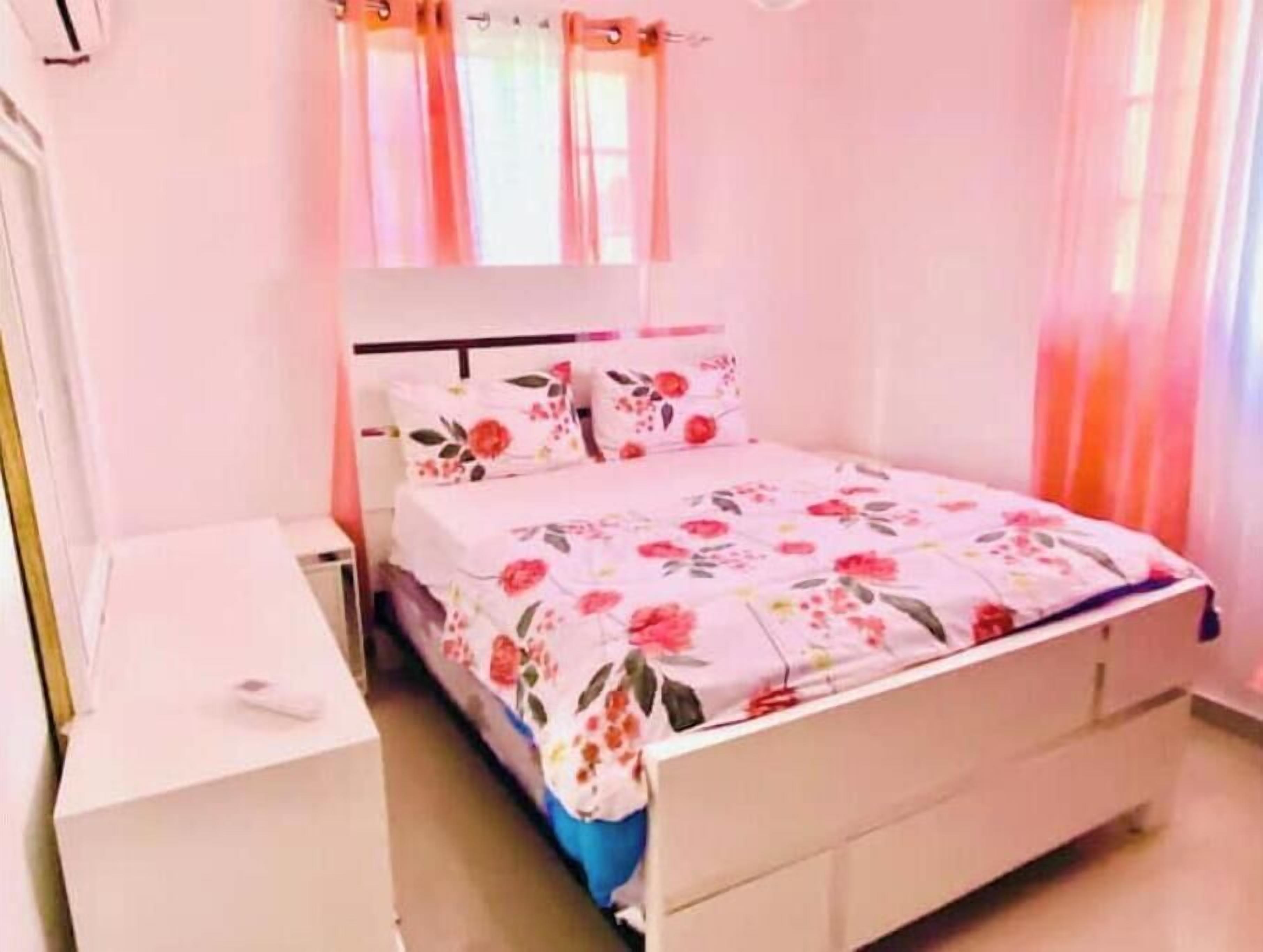 Ein Schlafzimmer mit einem Bett, einem Nachttisch und einem Fenster mit Vorhängen.