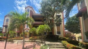 A multi-story building with a central courtyard, palm trees, and a bench. - Santo Domingo huge furnished longterm available apt (Santo Domingo norte)