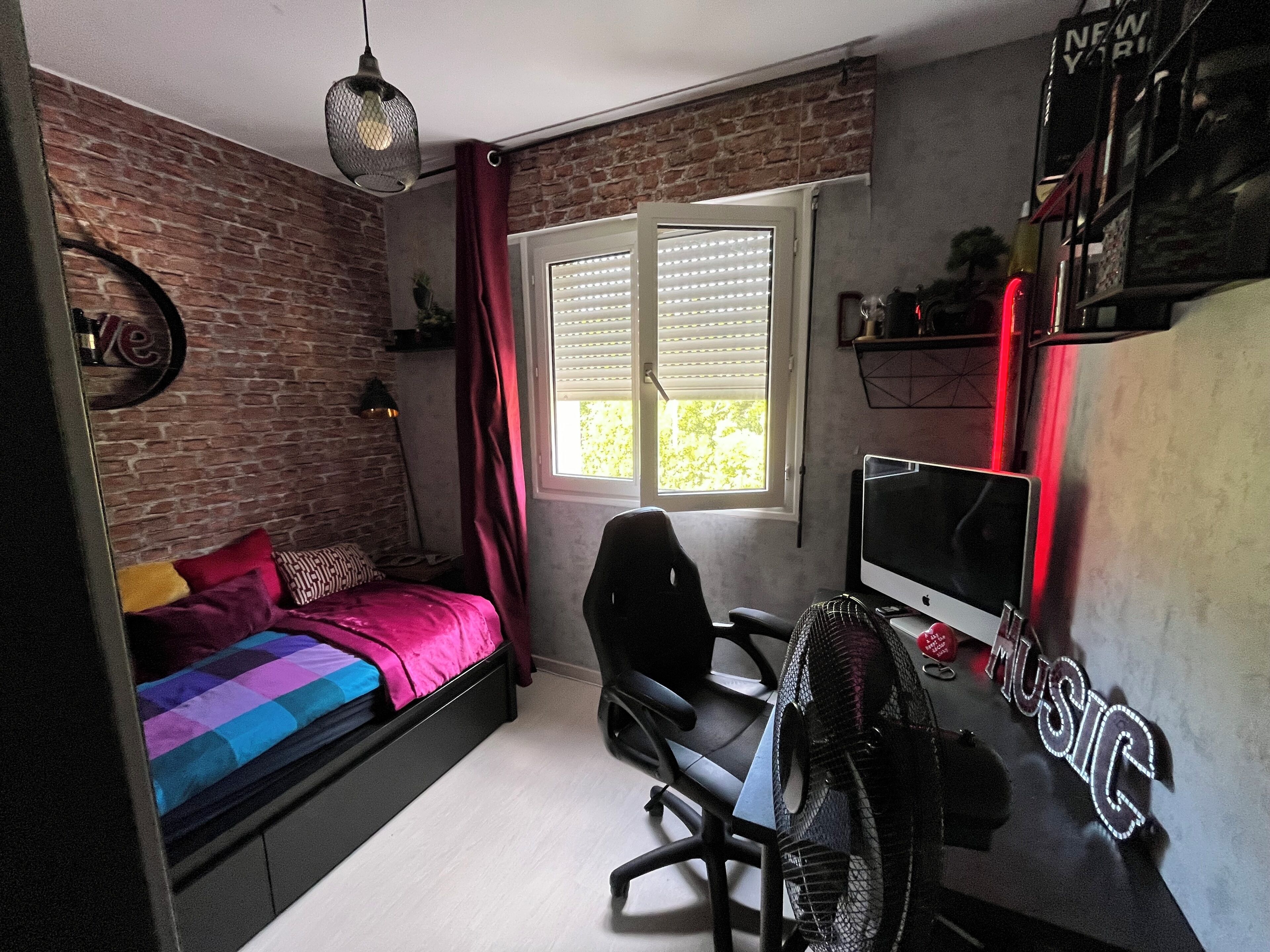 A bedroom with a bed, desk, chair, and a window with blinds.