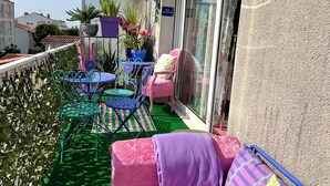 A balcony with a green floor, pink and purple furniture, and a blue decorative item. - Bohemian boudoir-style artist apartment. (Royan)