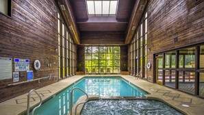 An indoor swimming pool with wooden walls and large windows, a hot tub, and safety signs. - Copper Chase 116 (Brian Head)