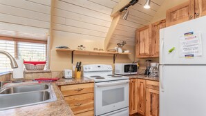 A kitchen with wooden cabinets, a white stove, a microwave, and a refrigerator.