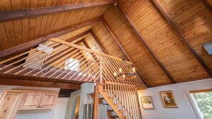 Ein Holzinnenraum mit Treppe, Holzbalken und einer hängenden Leuchte.
