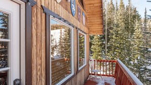Ein Holzhaus mit einer Holzdielenveranda und einem roten Geländer.