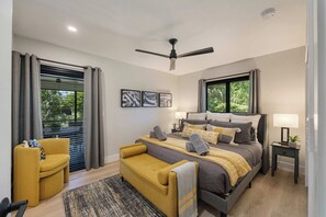 A modern bedroom with a bed, a sofa, a desk, and a ceiling fan.