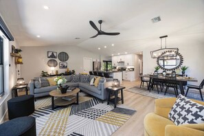 A modern living room with a sofa, coffee table, and a dining area with chairs and a table.