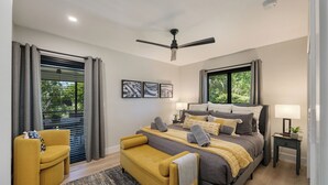 A modern bedroom with a bed, a sofa, a bedside table, and a ceiling fan.