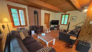 Un salon chaleureux avec une cheminée, un téléviseur et des fauteuils confortables.