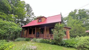 Une maison à deux étages avec un toit rouge et une véranda.