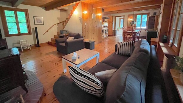 Un vaste espace de vie doté d’un plafond en bois, d’un ensemble de canapés, d’une table basse et d’un escalier menant à un autre niveau.