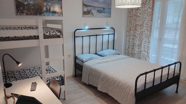 Un dormitorio con una litera, un escritorio con lámpara y una cama con ropa de cama estampada.