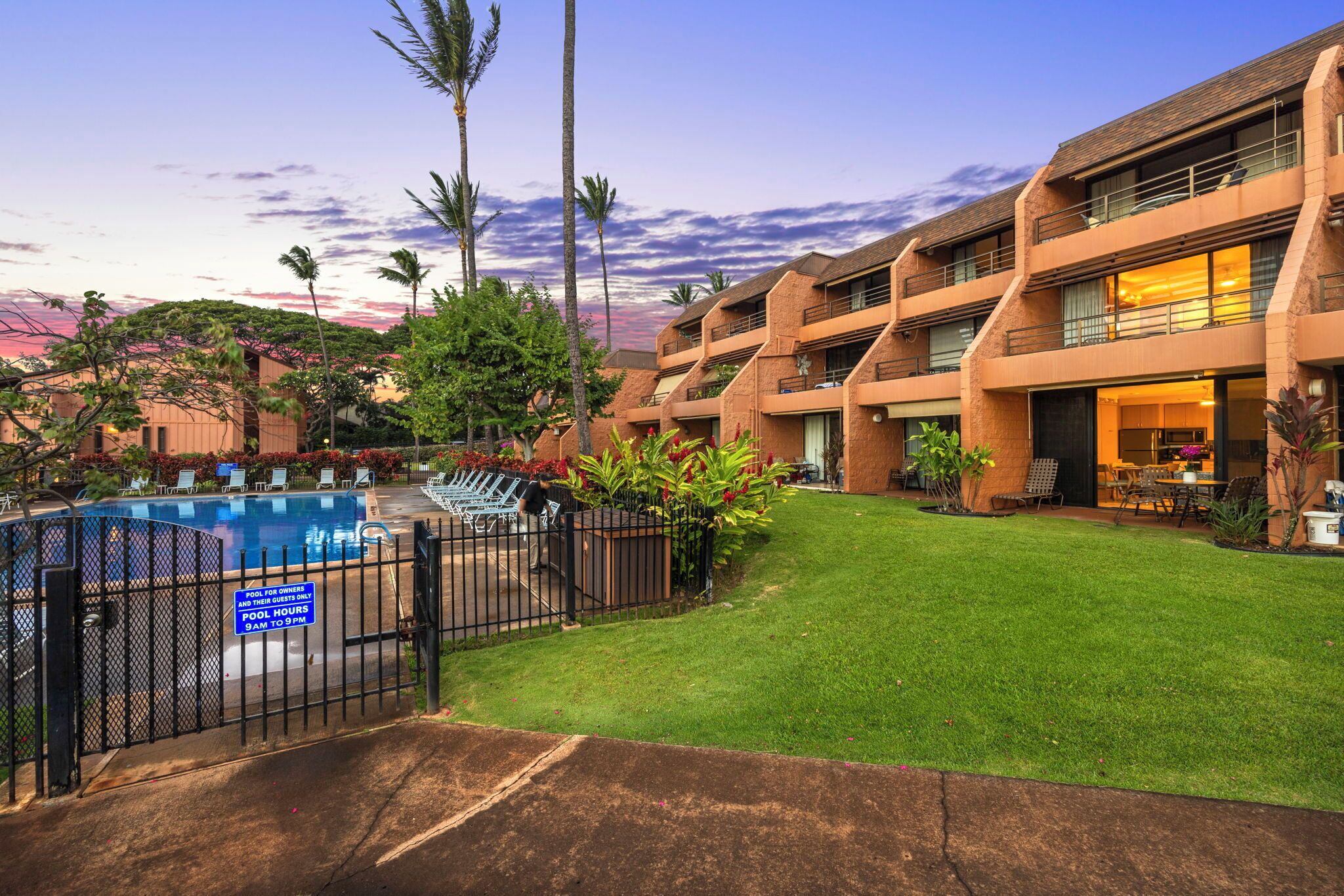 A hotel with a swimming pool, outdoor seating, and a well-maintained lawn.