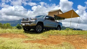 A silver SUV parked on a dirt path with a camping canopy. - Silver Fox Camper 2018 Tacoma (Anahola)