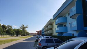 A row of parked cars in front of a modern apartment building with balconies. - Golden Lake (Arraial do Cabo)
