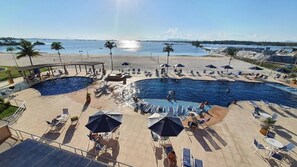 A resort with a large swimming pool, sun loungers, umbrellas, and a beach area. - Golden Lake (Arraial do Cabo)