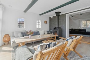 A modern living room with a fireplace, a sofa, a dining table, and a large window.
