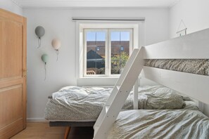 A bedroom with a bunk bed, a window with a view of buildings, and balloons on the wall.