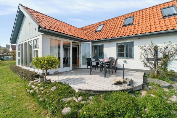 A modern house with a sloped roof, a deck, and a garden area.
