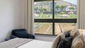 Ein Hotelzimmer mit einem großen Fenster, das einen Blick auf einen Hügel mit Gebäuden und Grünflächen bietet.