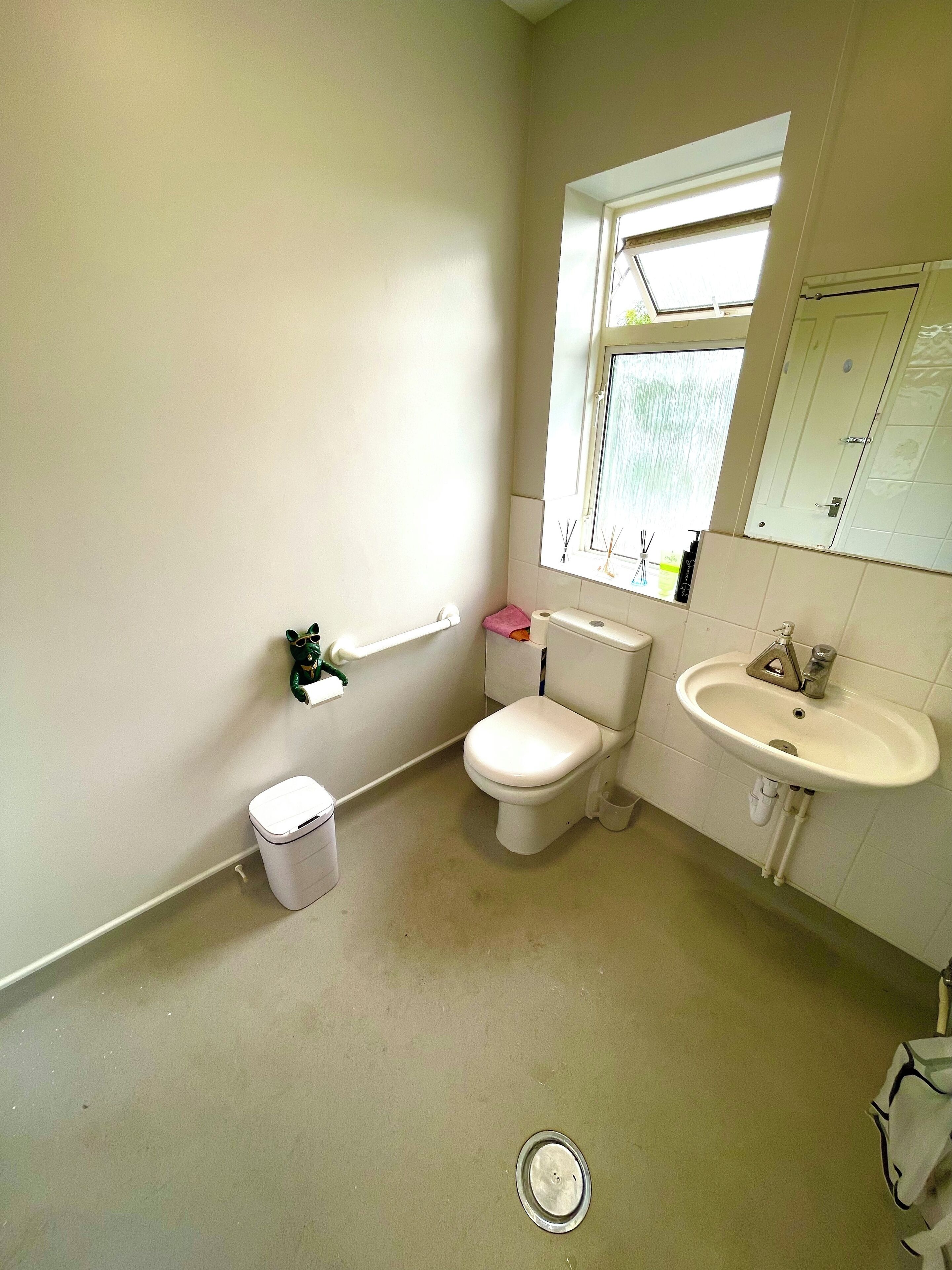 A small, clean bathroom with a toilet, sink, and window.