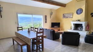 Amplia sala de estar con mesa de comedor, sofás, chimenea y televisor.