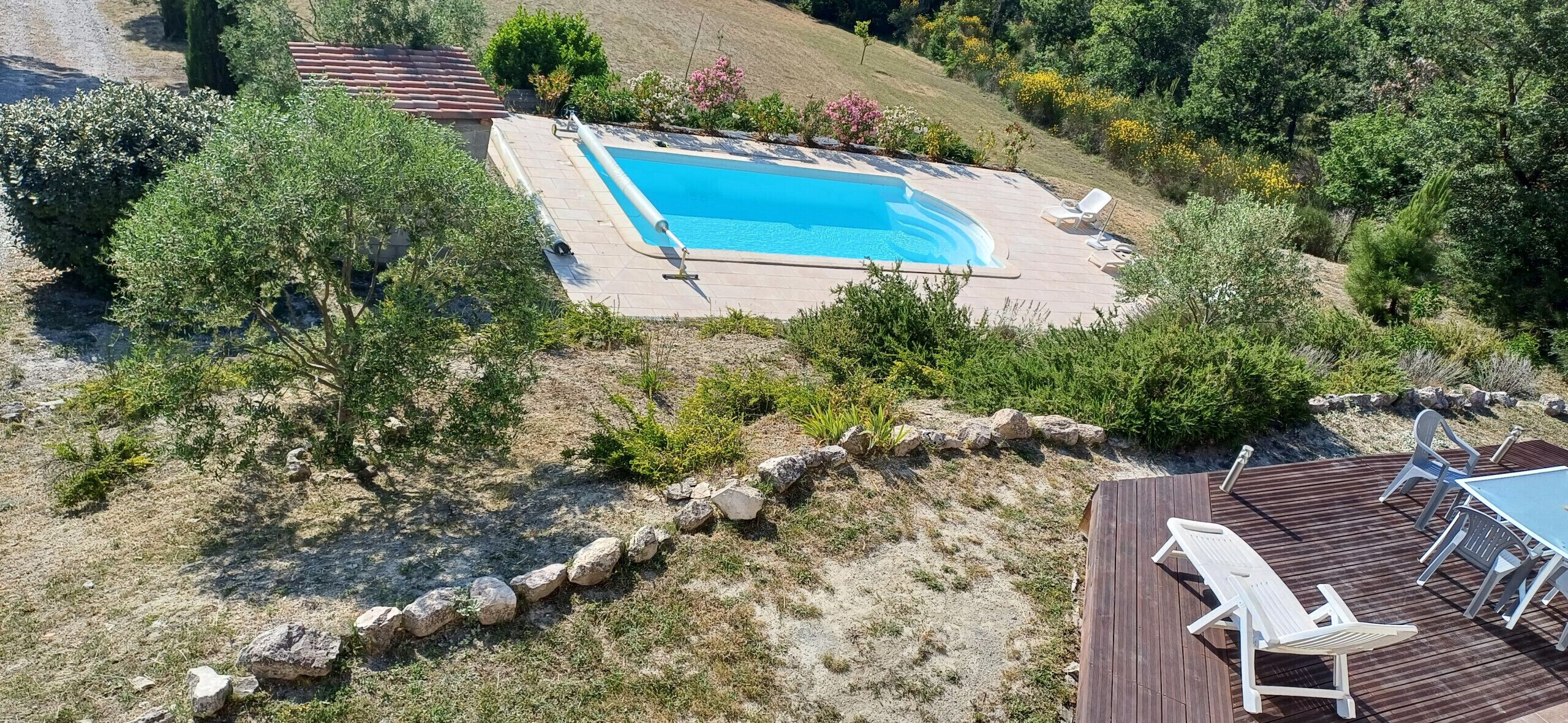 An aerial view of a swimming pool surrounded by a wooden deck with lounge chairs.
