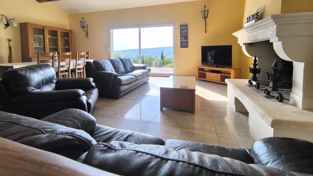 Una sala de estar con un sofá, un televisor, una chimenea y un comedor con mesa y sillas.