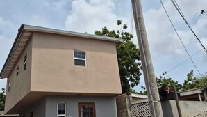 A two-story building with a flat roof and a red door.
