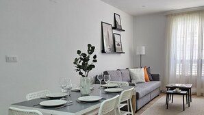 A modern living room with a dining area, featuring a sofa, a coffee table, and a dining table set for four. - Chic Escape Apartment (Godella)