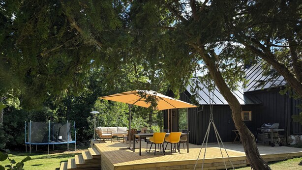 Een houten terras met buitenmeubilair, een hangmat en een schommel.