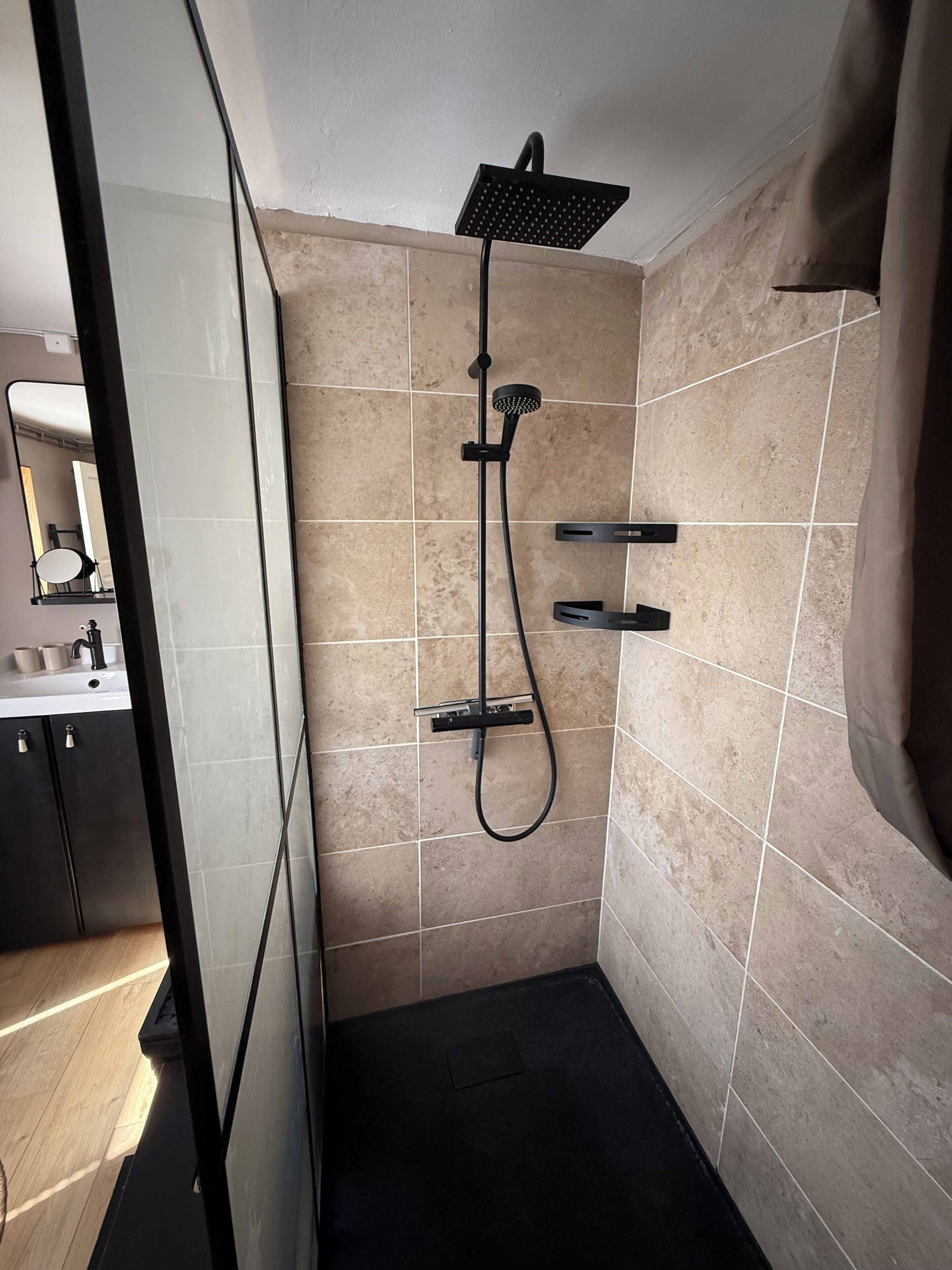Un baño moderno con ducha, espejo y lavabo.