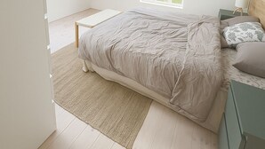 Een slaapkamer met een schuine kap, dakramen, een bed, een nachtkastje en een raam.