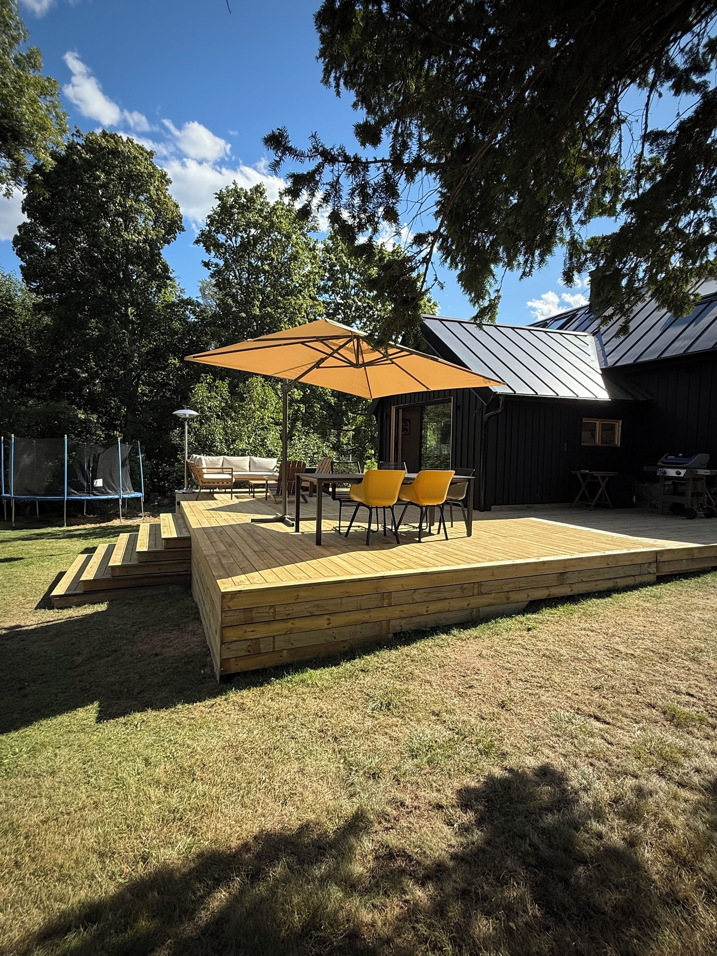 A wooden deck with outdoor furniture and a large umbrella.