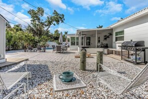 Un patio con mobiliario exterior, una parrilla y una zona de piscina.