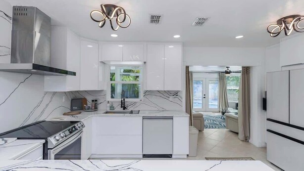 A modern kitchen with white cabinetry, a built-in stove, and a central island. - NEW! Tropical Paradise with Pool! 5 mins to beach! (St. Petersburg)