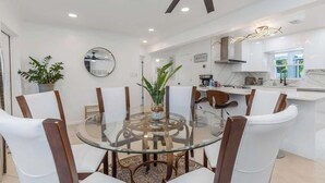 A modern kitchen with white cabinets, a glass dining table, and a ceiling fan. - NEW! Tropical Paradise with Pool! 5 mins to beach! (St. Petersburg)