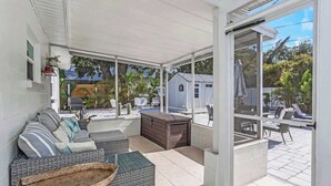 A covered patio area with a sofa, a wooden chest, and a wicker basket. - NEW! Tropical Paradise with Pool! 5 mins to beach! (St. Petersburg)