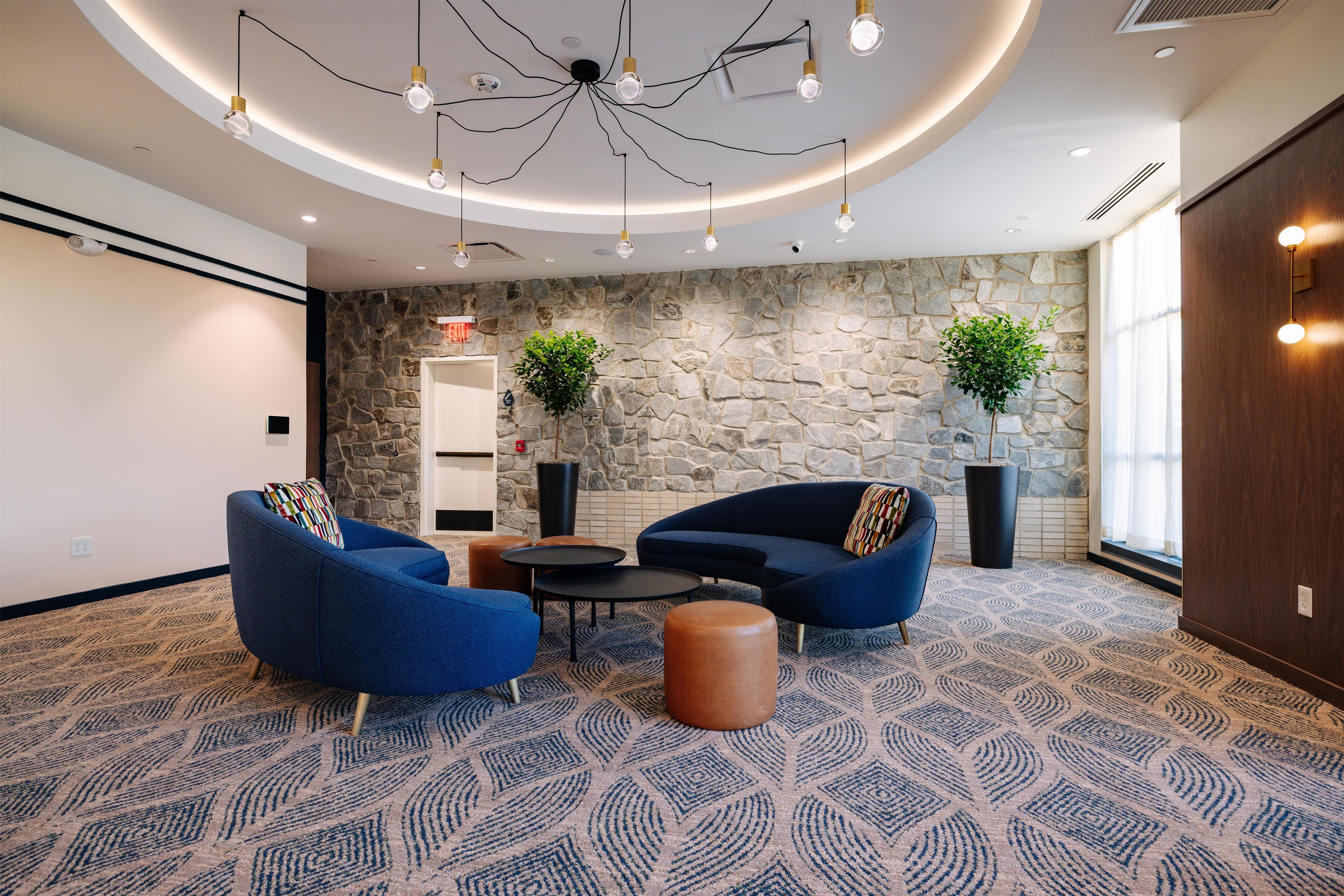 A modern lounge area with blue sofas, a coffee table, and a stone accent wall.